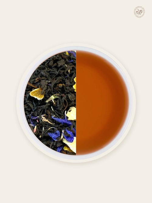 Lady Grey black tea with orange peel and blue cornflowers beside deep mahogany tea liquor